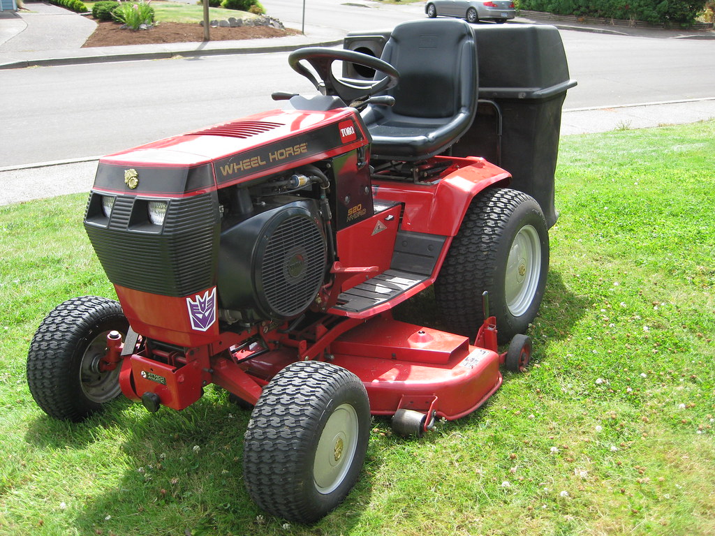 A red Wheel Horse 520 garden tractor with a black vinyl seat and a mower deck slung underneath, parked on a suburban lawn.